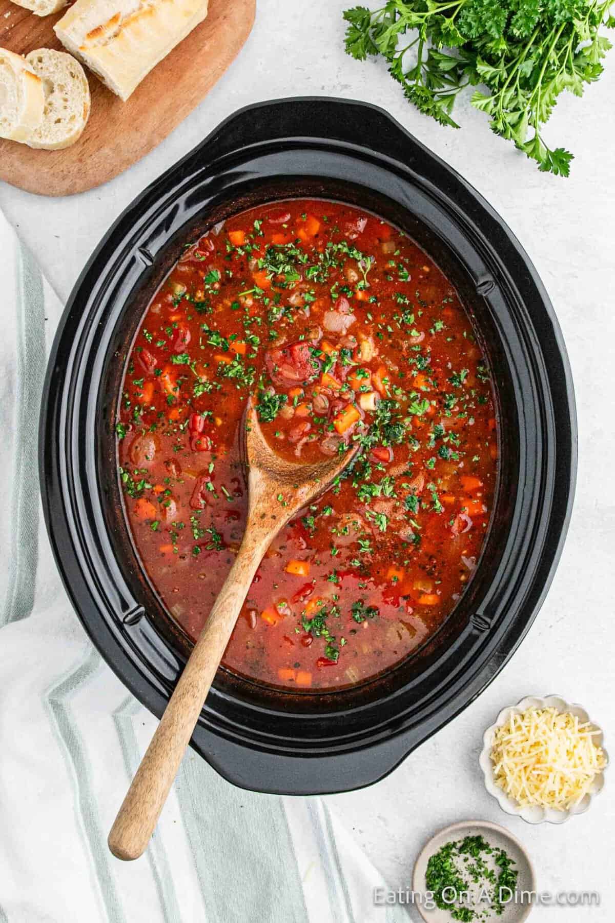 Cooked pasta fagioli in the crock pot with a wooden spoon