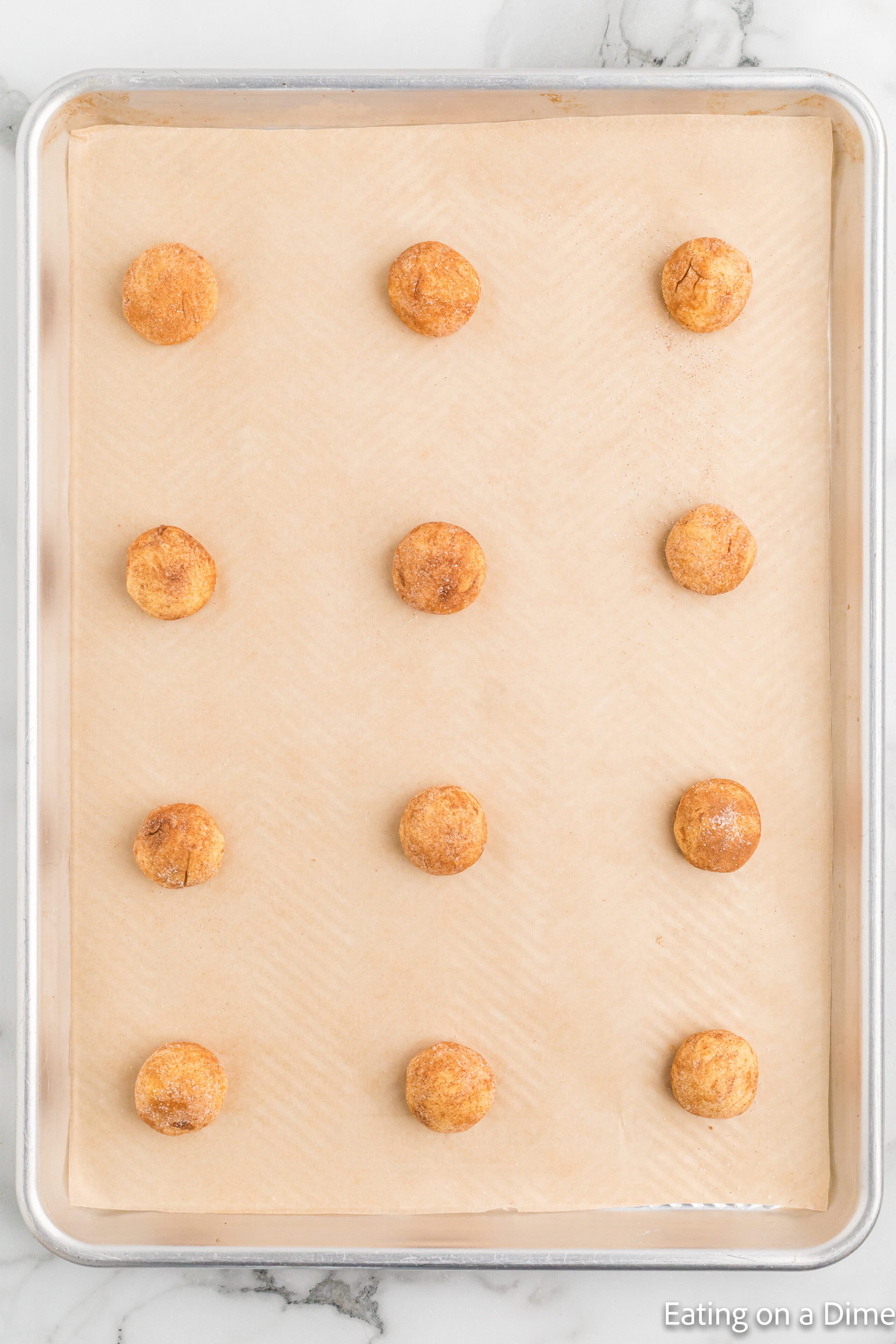 Snickerdoodle cookie dough balls on a baking sheet