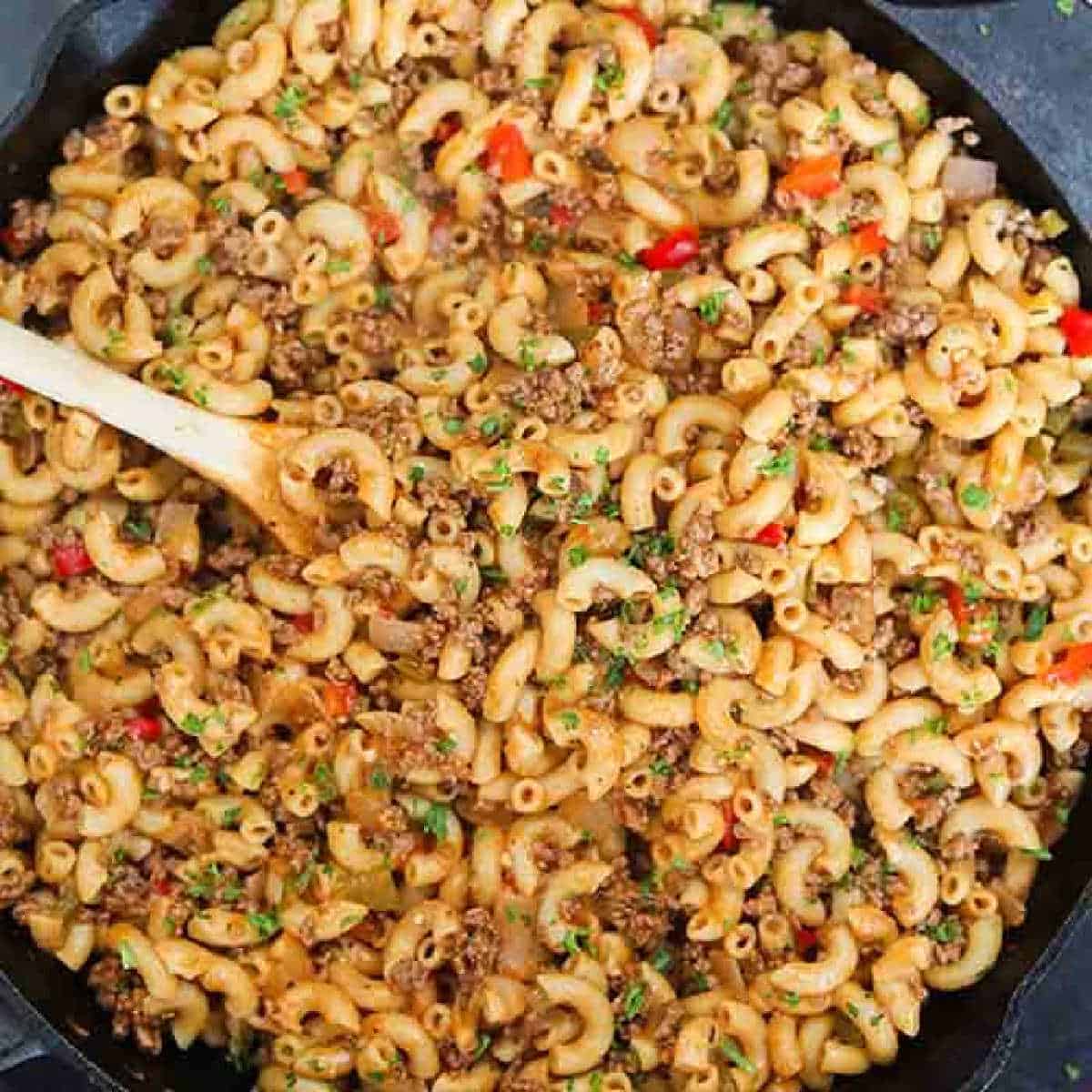 A large spoon scooping out a serving of a beef and macaroni meal.
