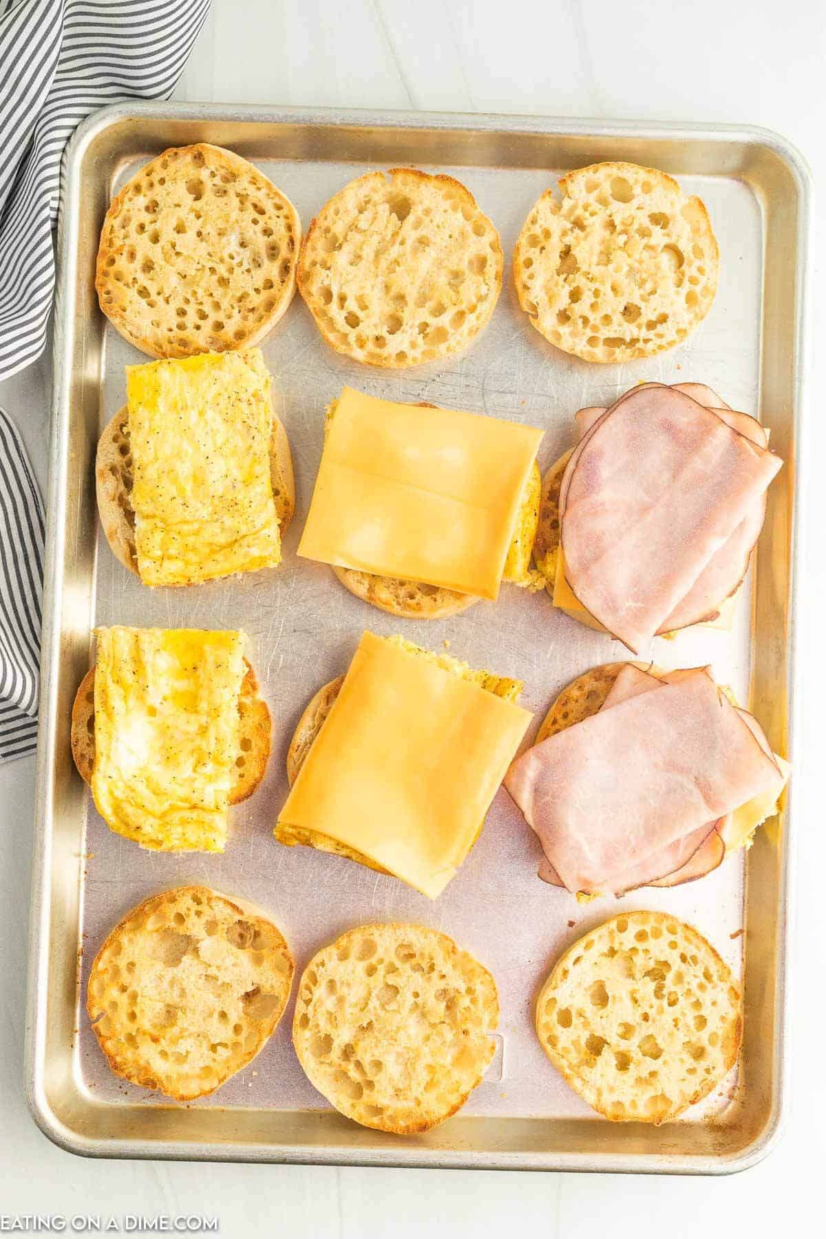 Topping the toasted English Muffins with egg, cheese and ham
