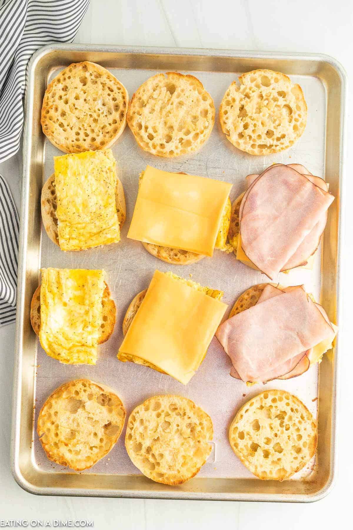 Topping the toasted English Muffins with egg, cheese and ham