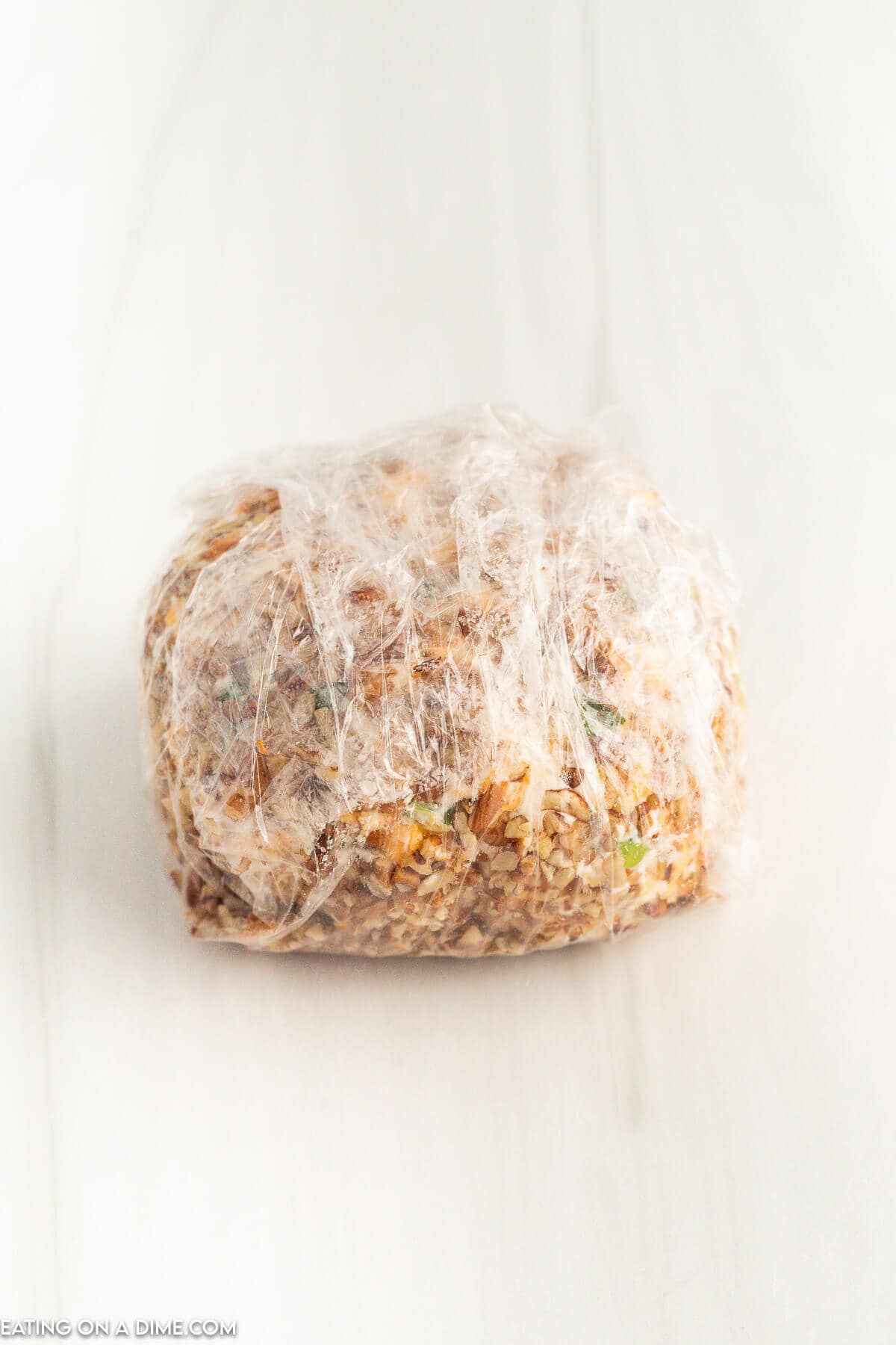 Cheese ball wrapped in plastic wrap and ready to serve