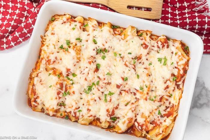 Stuffed Shells in a 9X13 baking dish topped with cheese and fresh parsley 