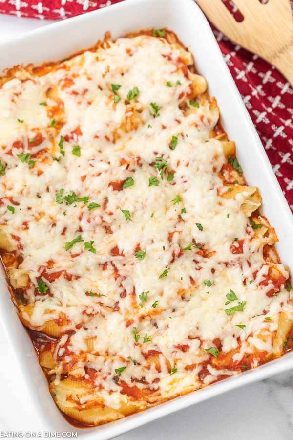 Stuffed Shells in a 9X13 baking dish topped with cheese and fresh parsley 