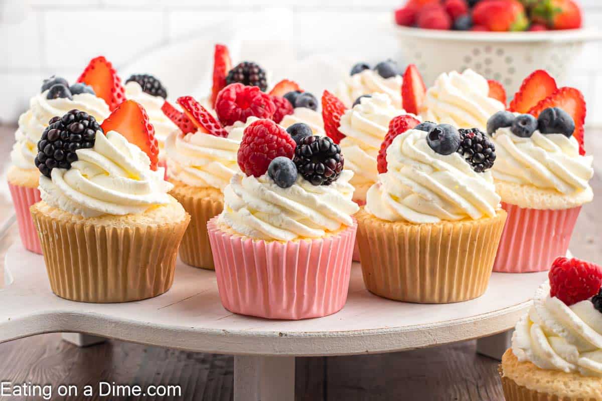 Angel Food cupcakes on a cake stand topped with fresh berries and cool whip