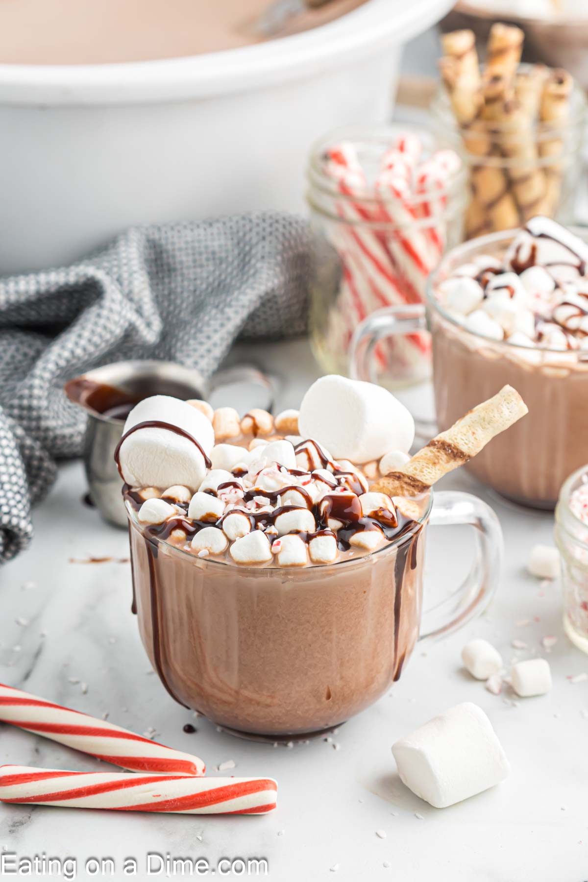 Hot Chocolate in a clear mug topped with marshmallows chocolate syrup and crushed peppermint