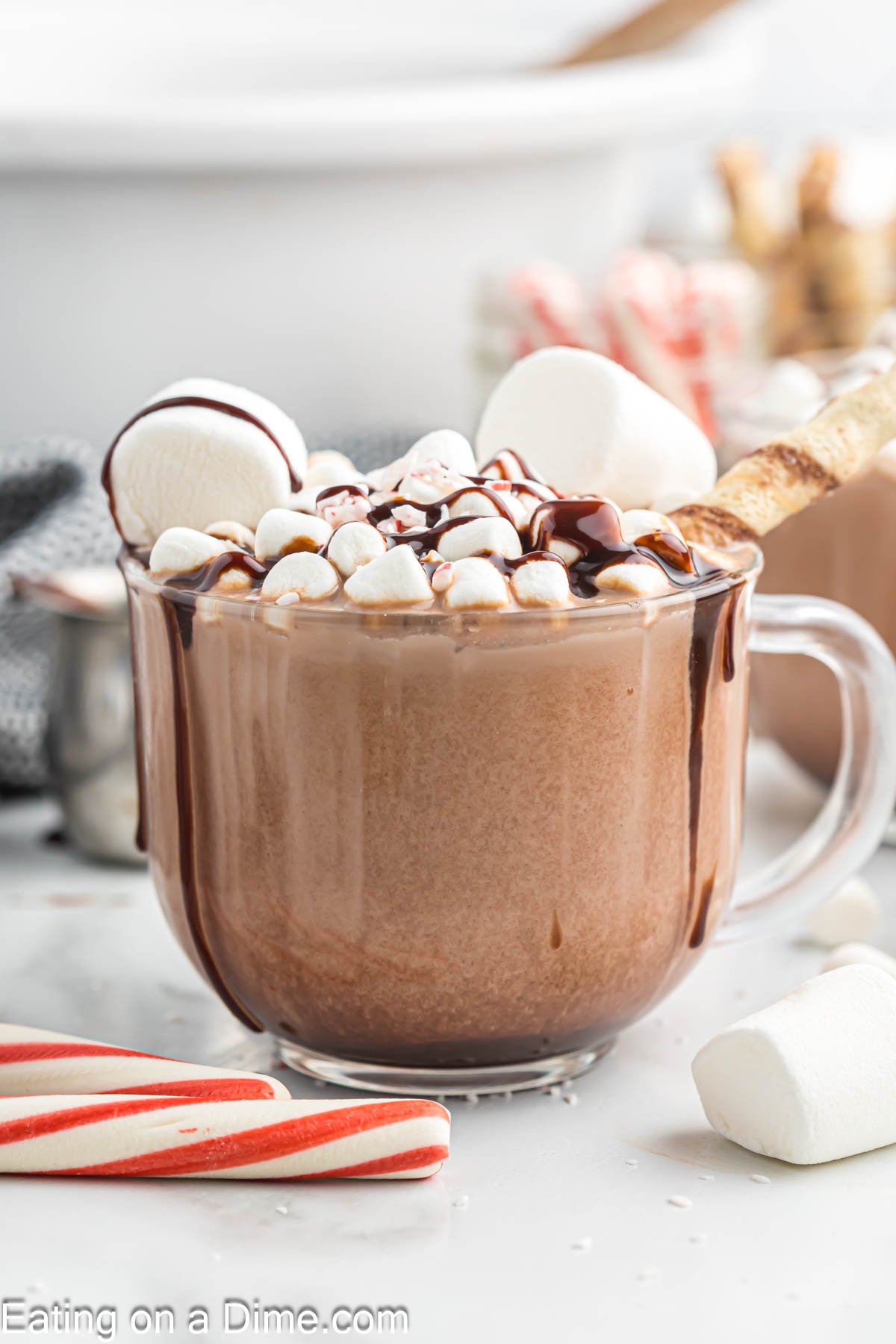 Hot Chocolate in a clear mug topped with marshmallows a drizzle of chocolate syrup and crushed peppermint