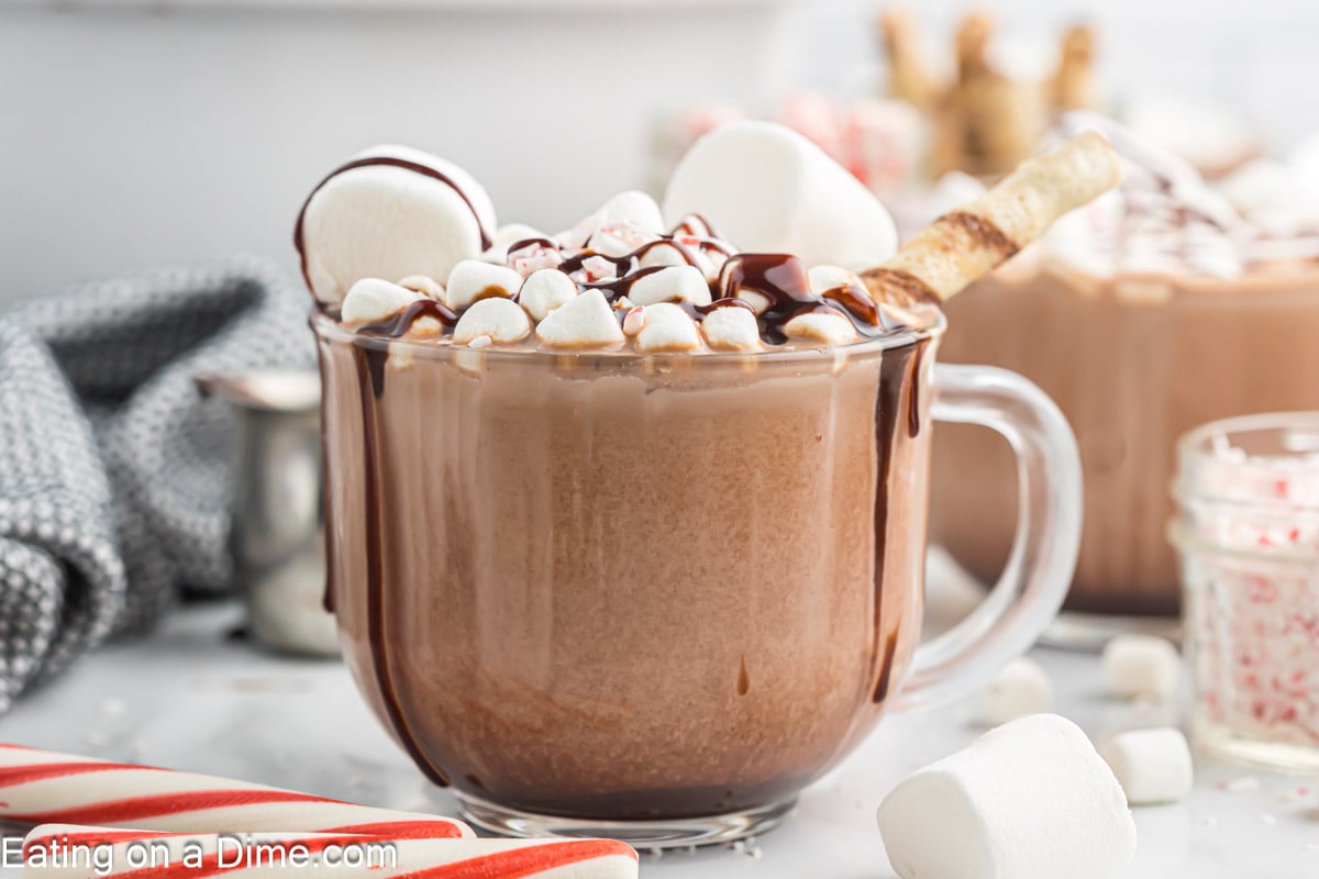 Hot Chocolate Mix in a clear mug topped with marshmallows, crushed peppermint with a drizzle of chocolate