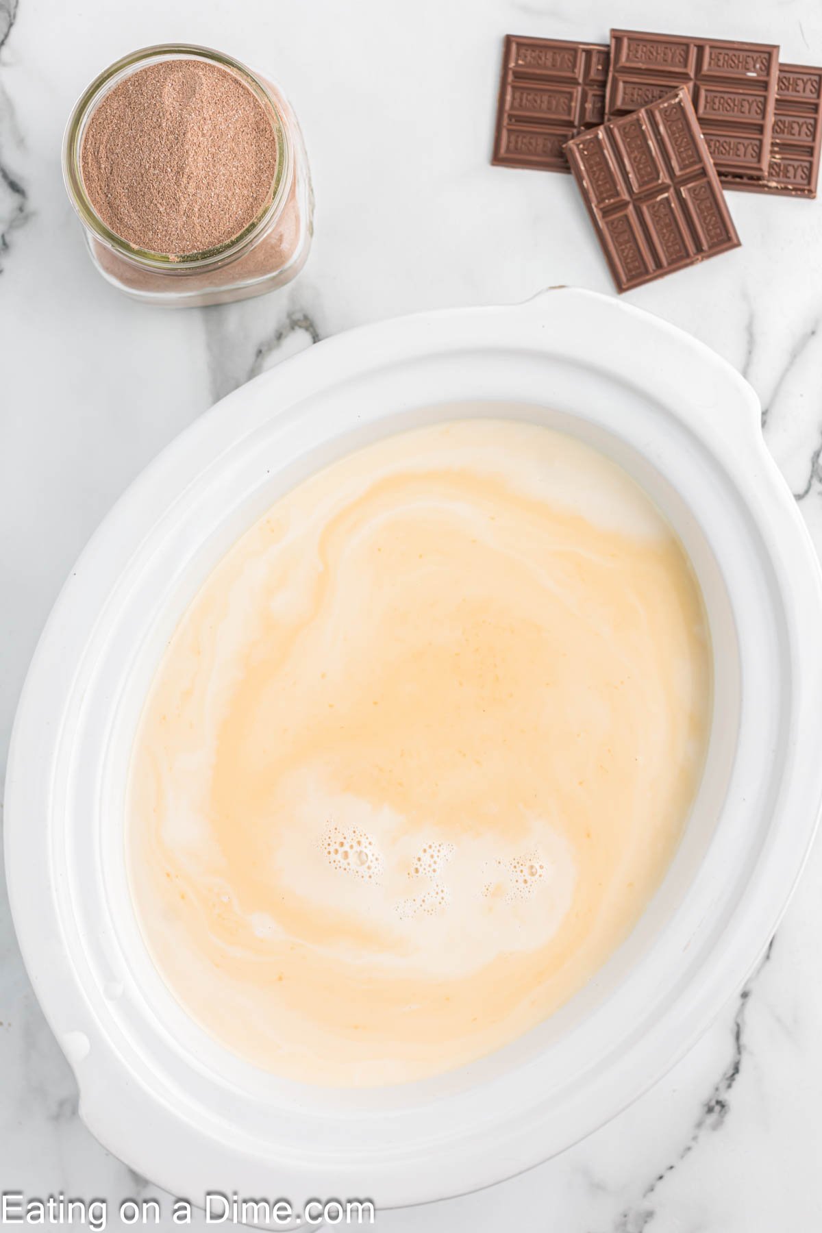 Pouring the milk, heavy cream and vanilla in the slow cooker