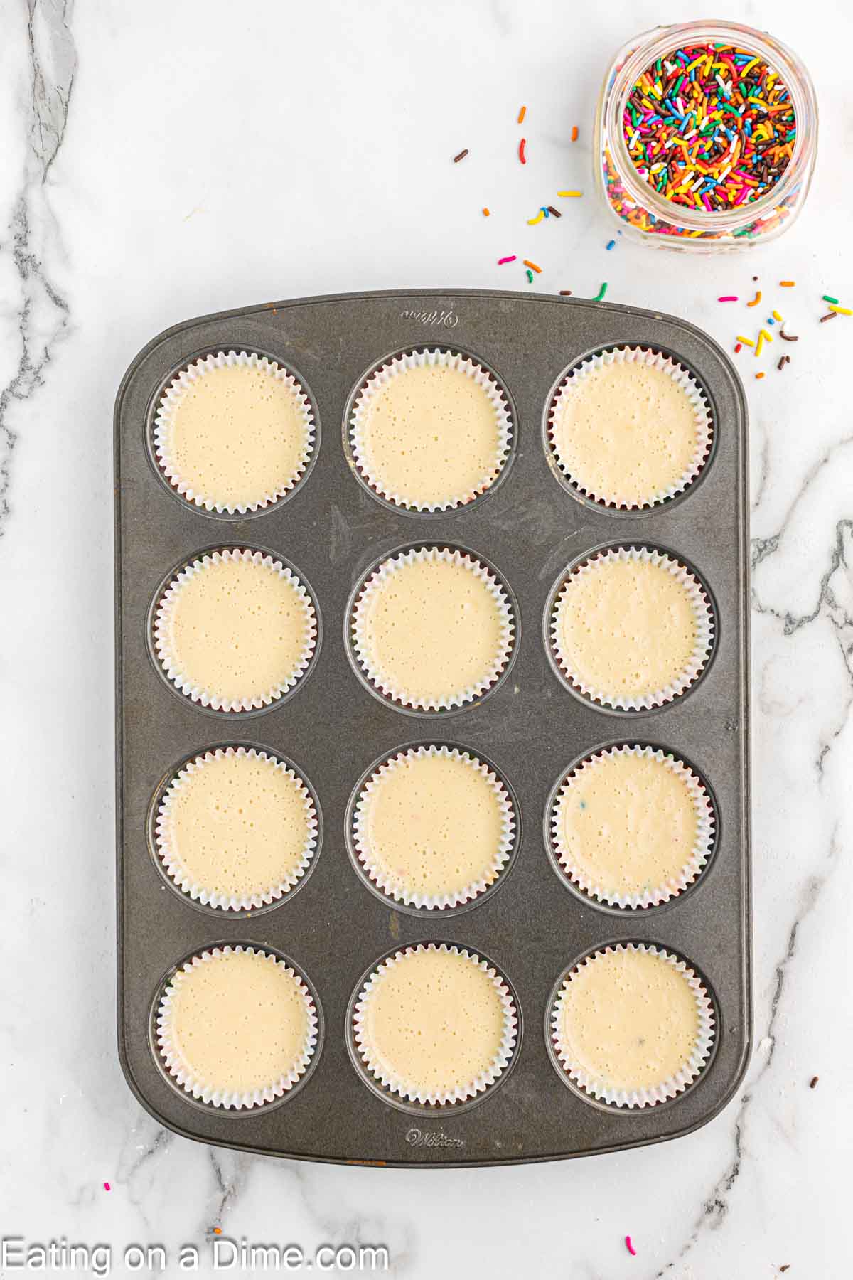 Dividing the cupcake batter into paper liners in a cupcake pan