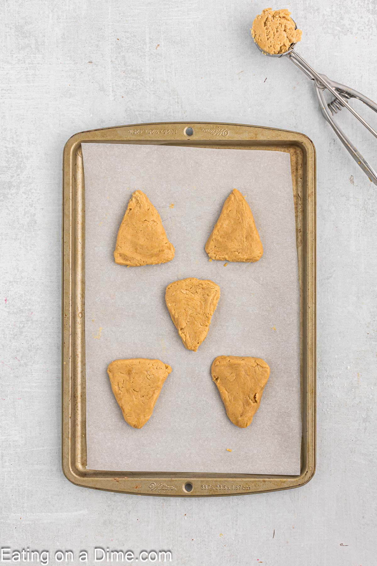 Scoop cookie dough with cookie scoop and shape into a triangle and place on a baking sheet