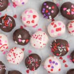 Chocolate covered valentine's day cake balls on a white surface.