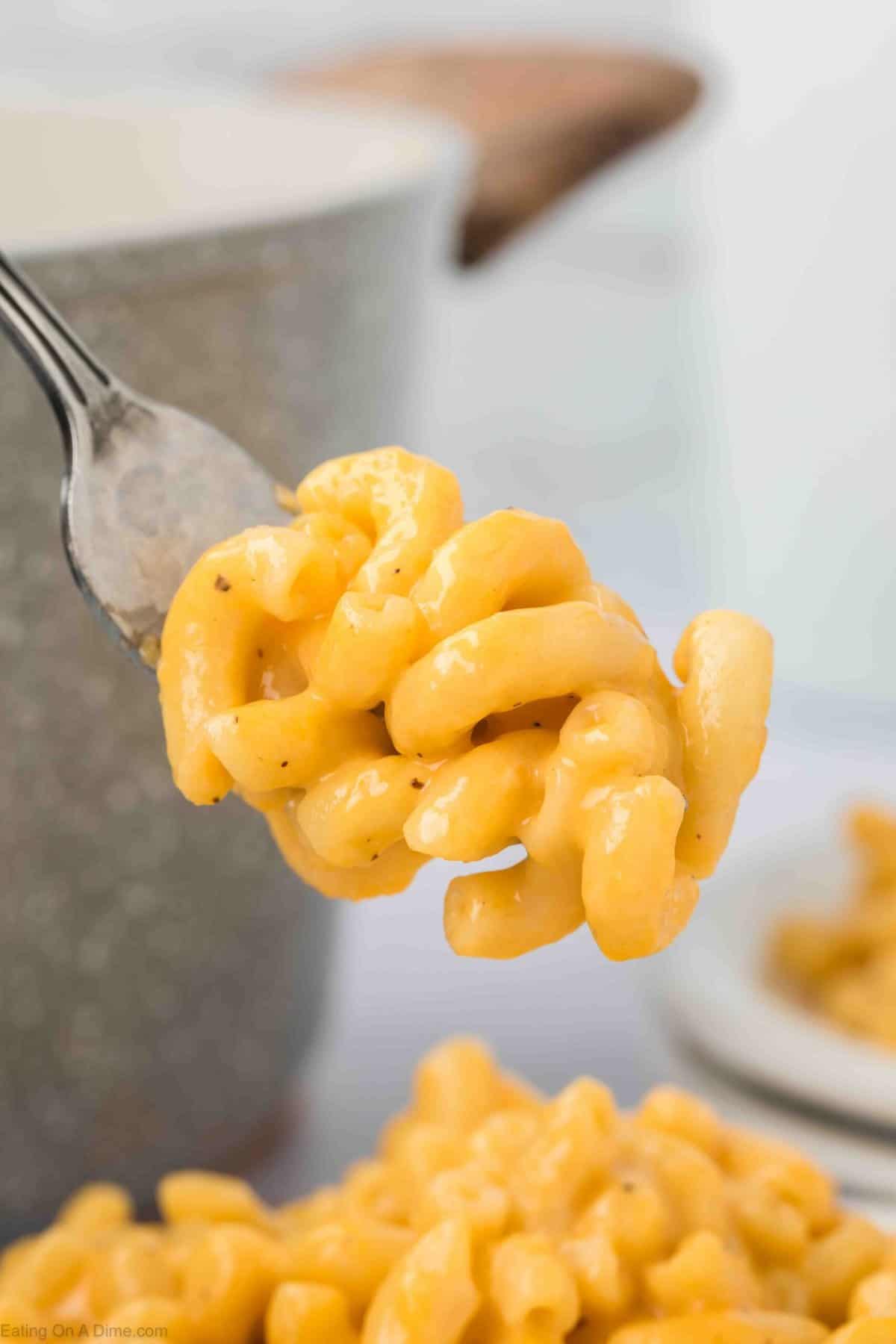 A close-up of a fork holding a bite of creamy, cheesy macaroni and cheese.