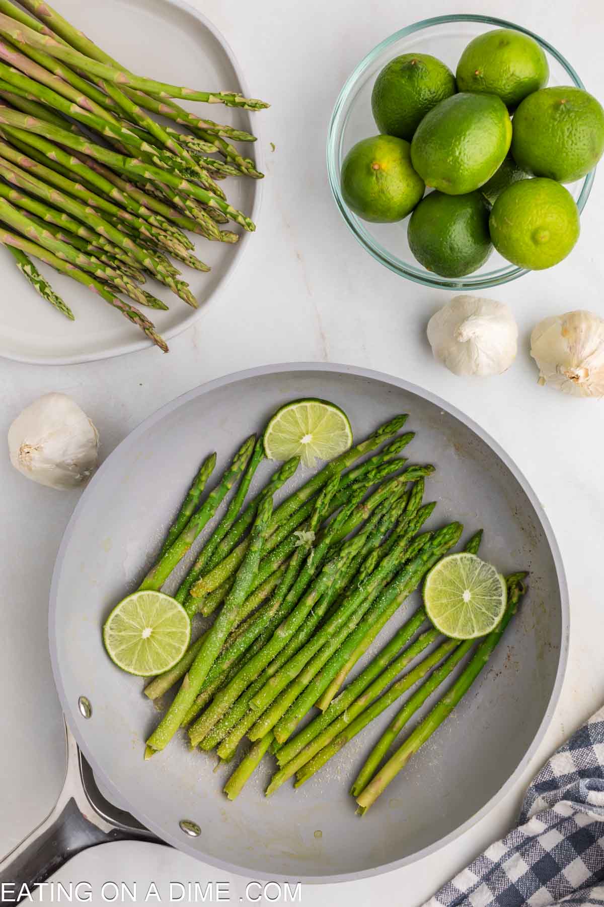 Steamed asparagus in a skillet topped with fresh limes