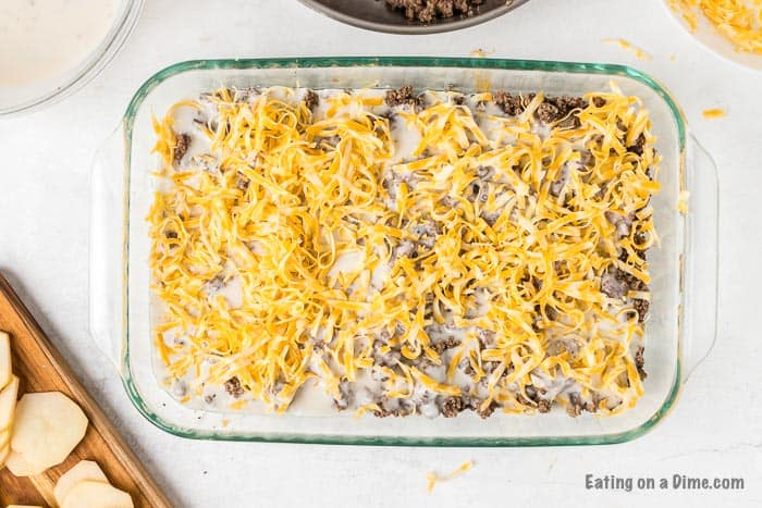 Layering slice potatoes, soup mixture, cooked ground beef and top with shredded cheese in a casserole dish