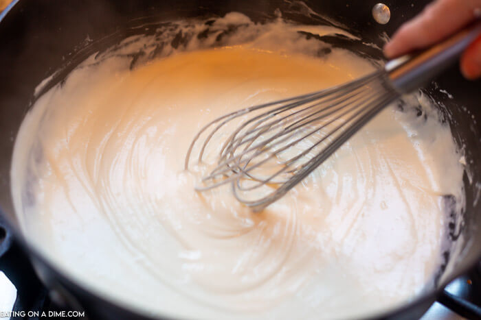 Close up image of the milk and flour being whisked in a iron skillet. 
