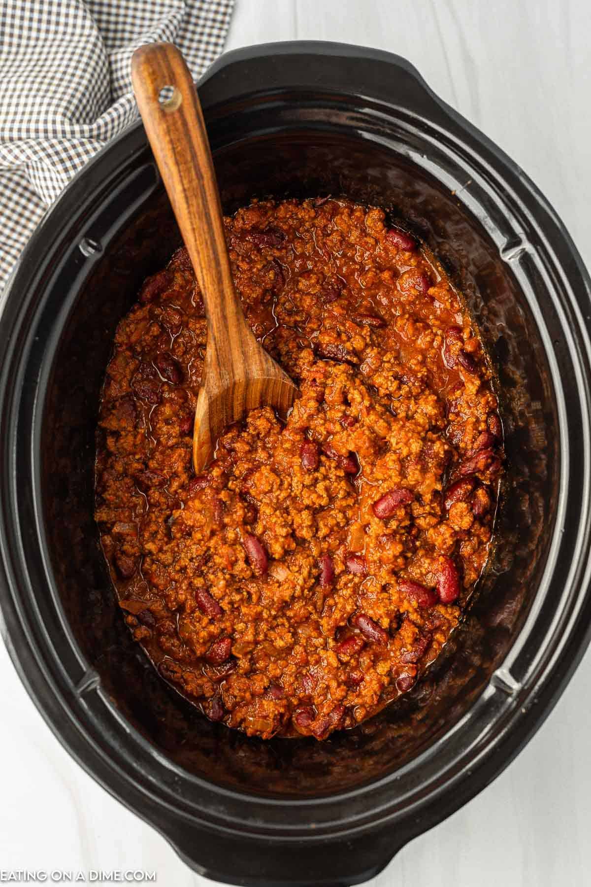 Chili in a crock pot with a wooden spoon