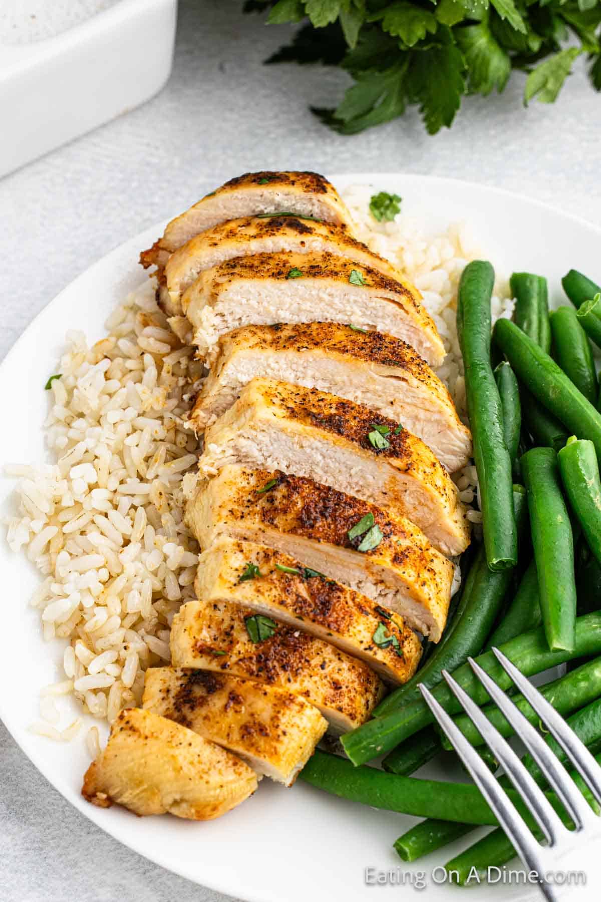 Slice cooked chicken breast on white rice with a side of green beans