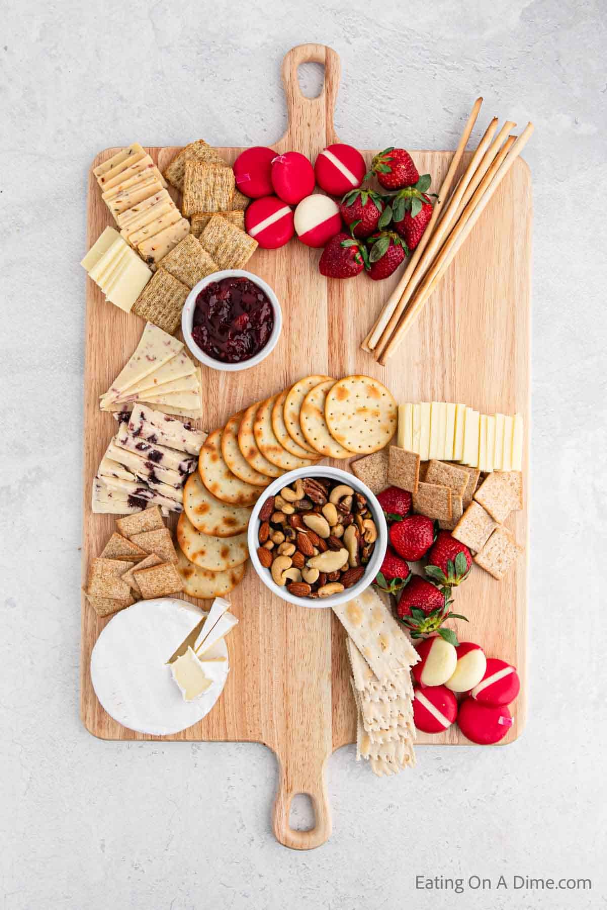 Placing cheese, crackers, fruit, meats on the board