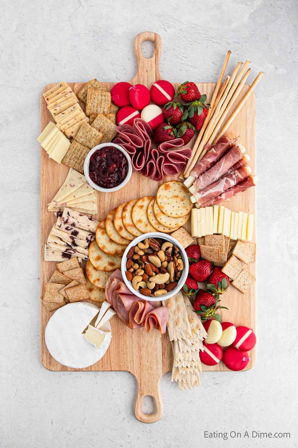 Placing cheese, crackers, meats on the charcuterie board