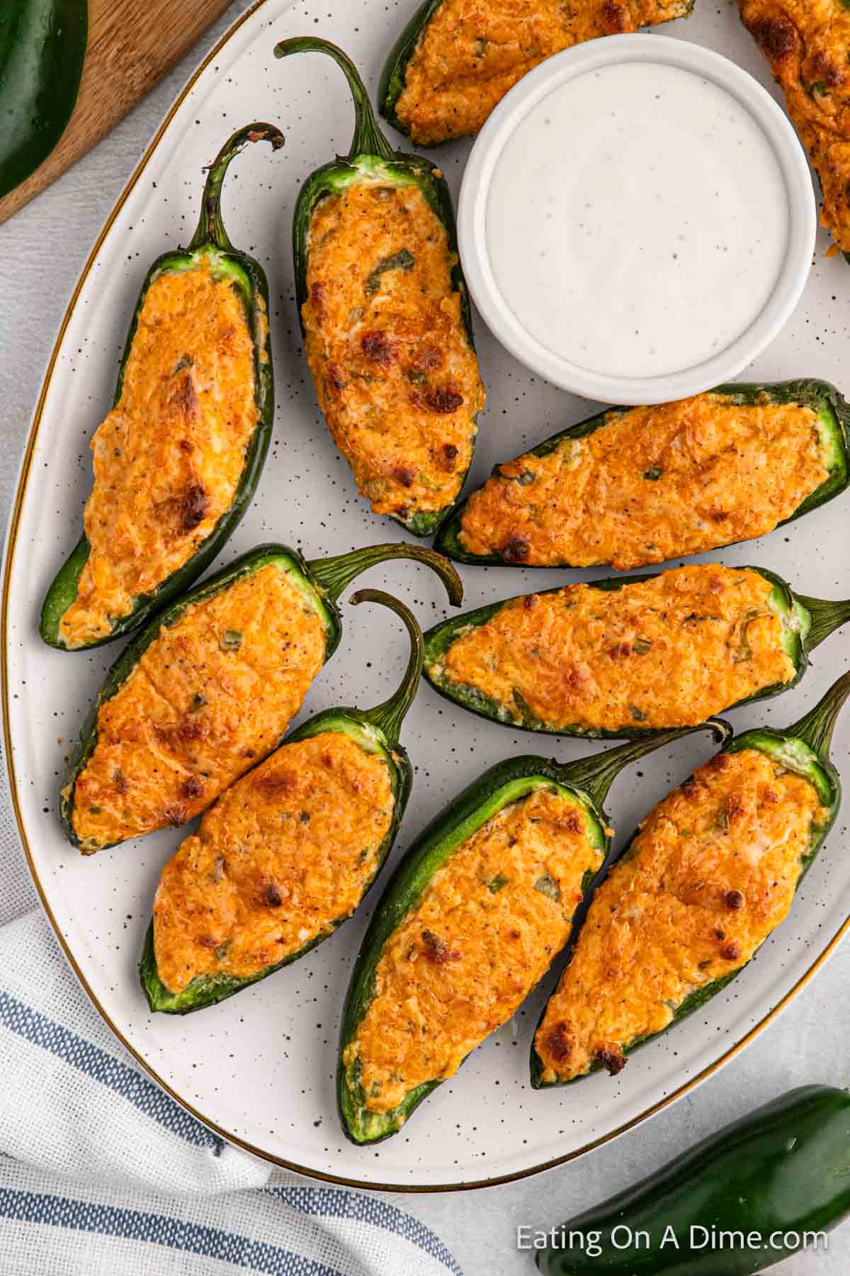 Jalapeno topped with golden brown cheese on a plate with a side of ranch in a bowl