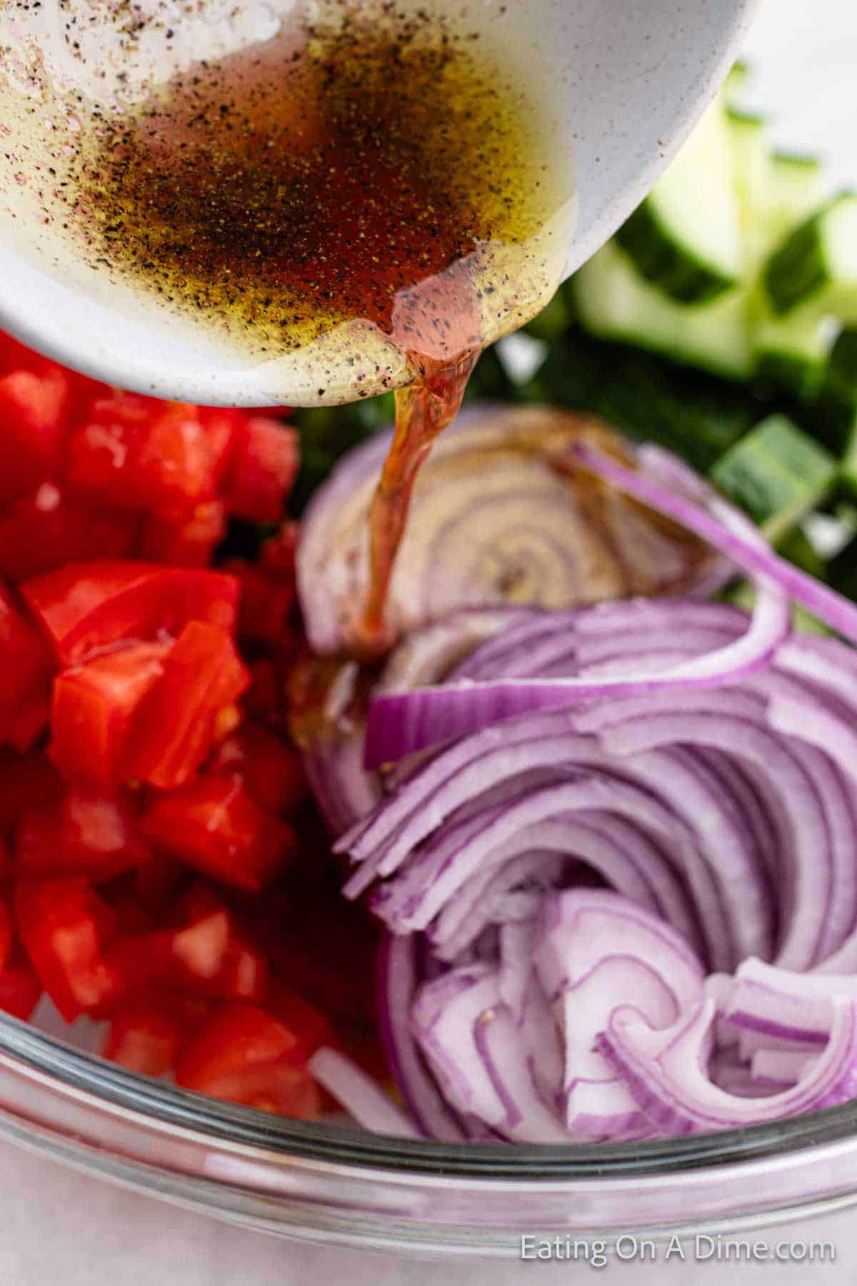 Pouring dressing over the tomatoes and red onions