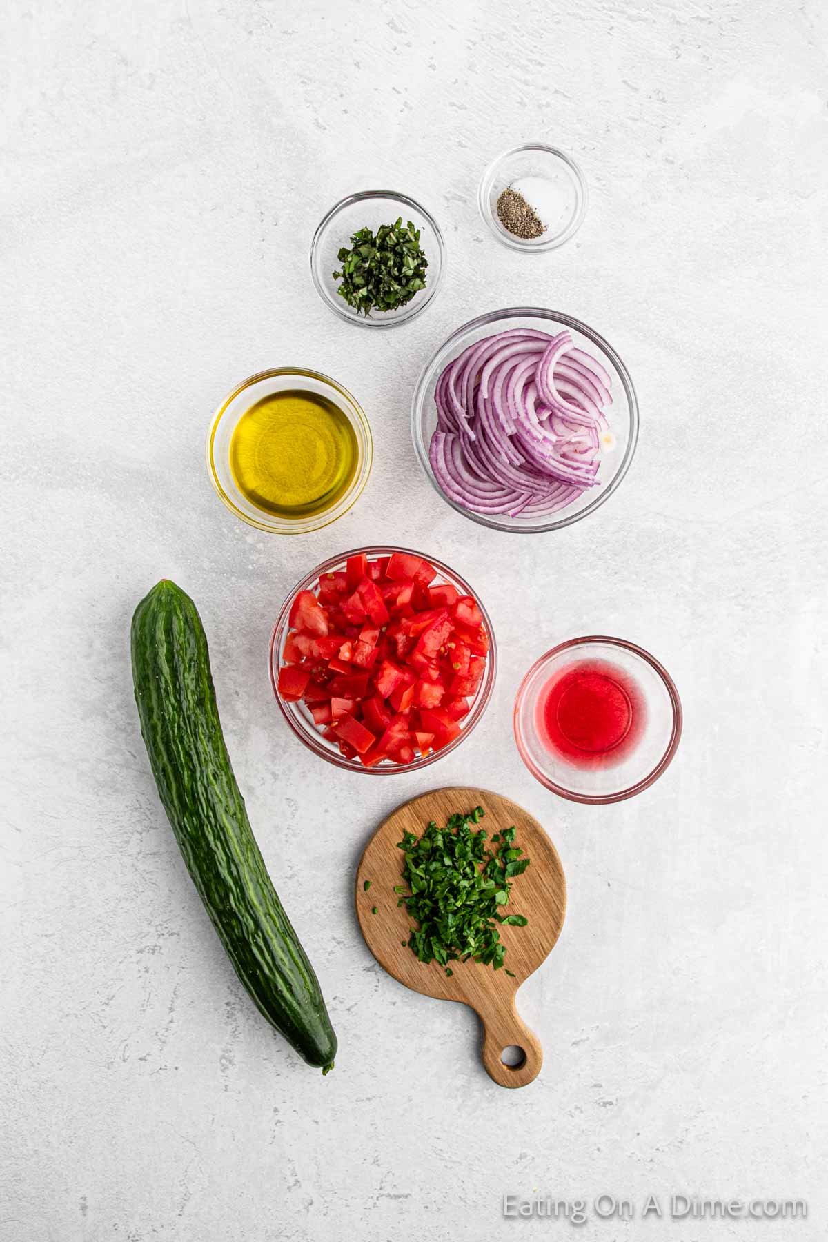 Cucumber tomato salad ingredients - English cucumber, tomatoes, red onion, olive oil, red wine vinegar, salt, pepper, parsley, basil