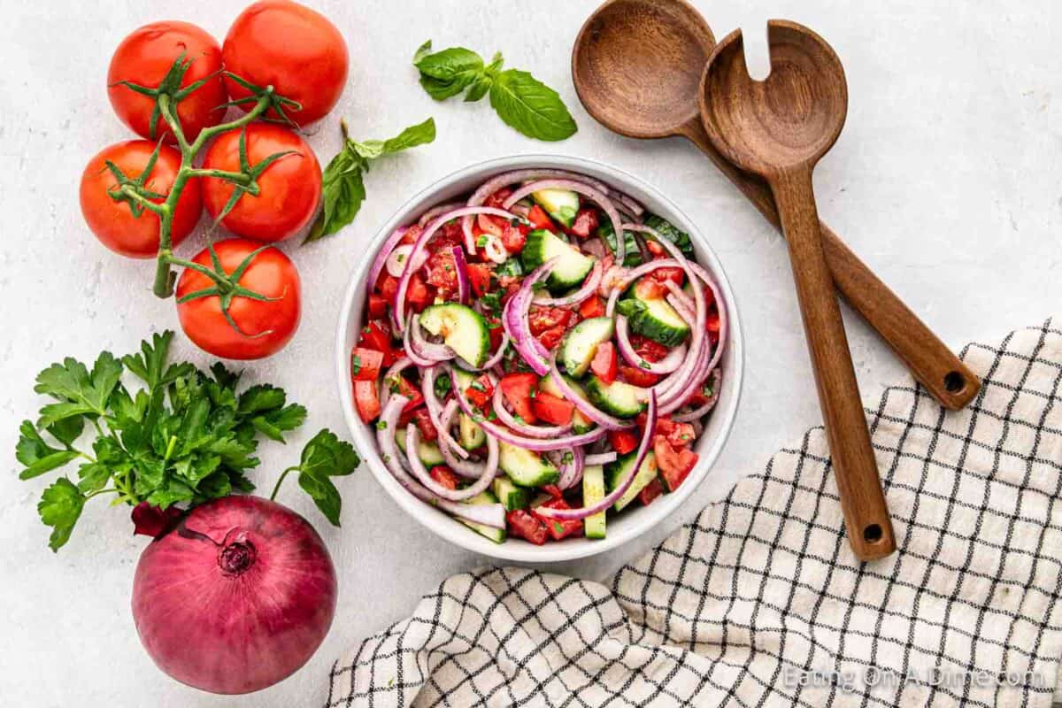 Cucumber tomatoes salad in a bowl with fresh tomatoes and whole red onions
