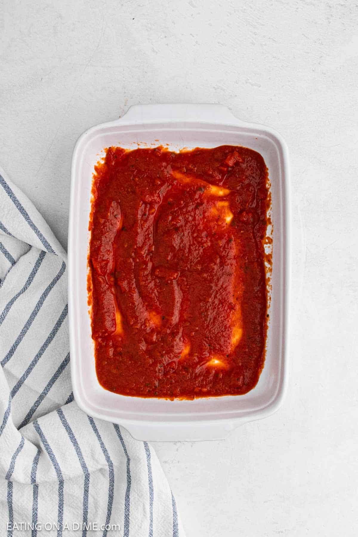 Marinara sauce spread in a white baking dish.