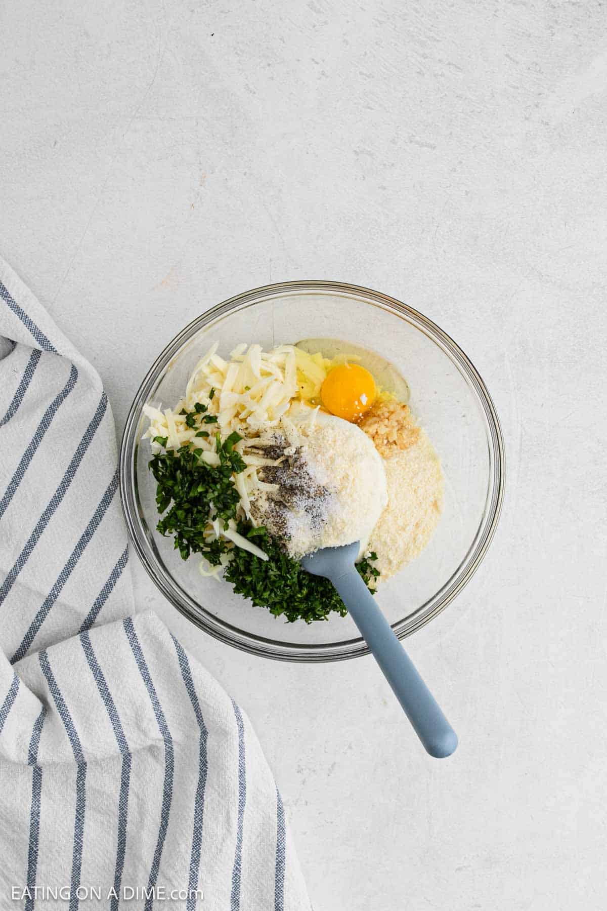 Ricotta cheese, mozzarella cheese, egg, parsley and spices in a bowl.