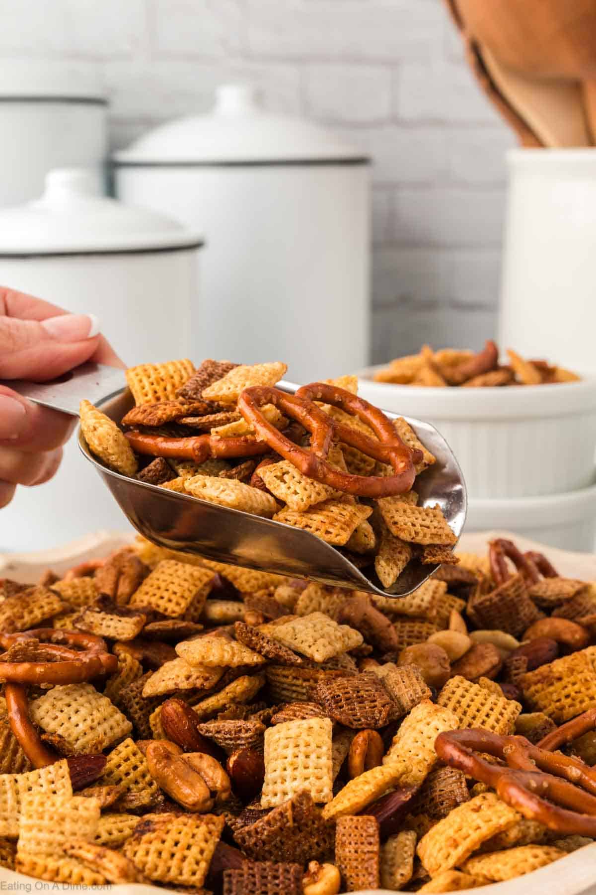 Chex Mix in a bowl with a serving a silver scoop