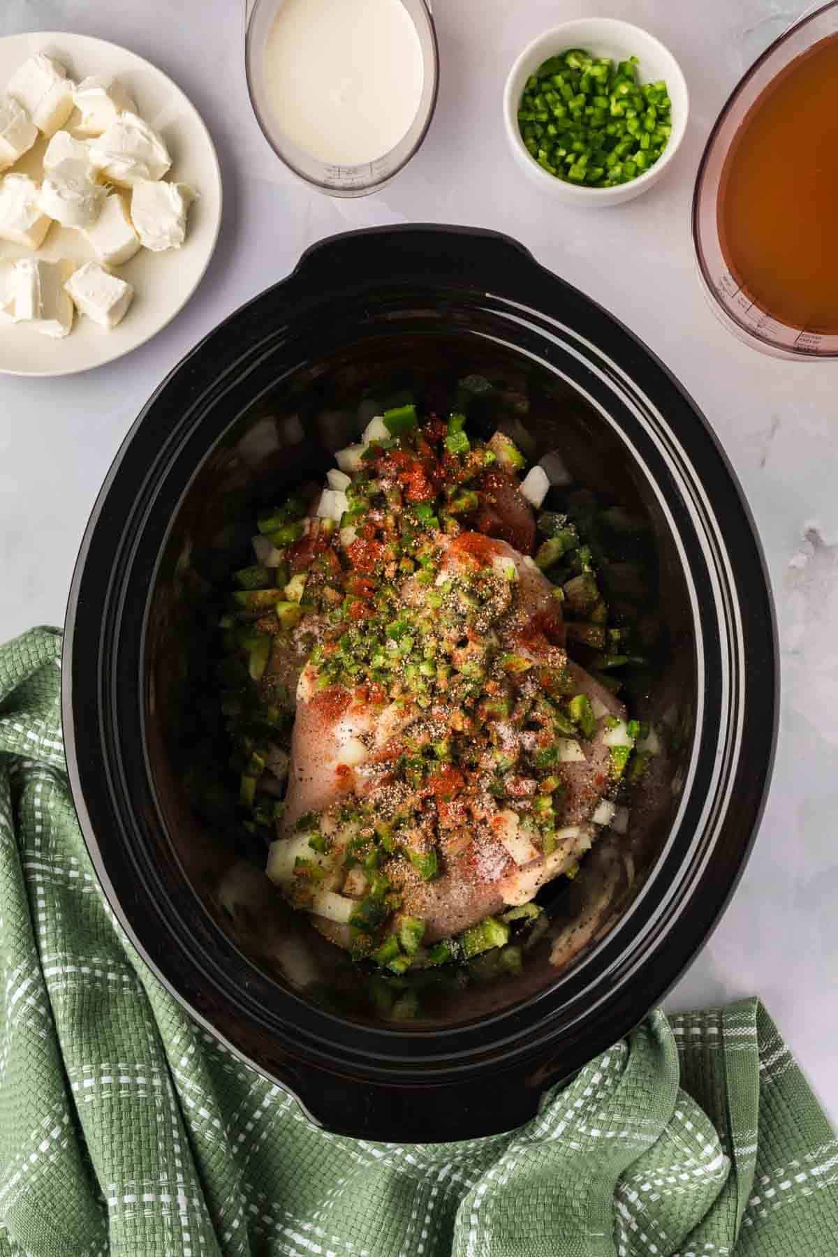 Chicken, chopped vegetables and seasoning place in a slow cooker