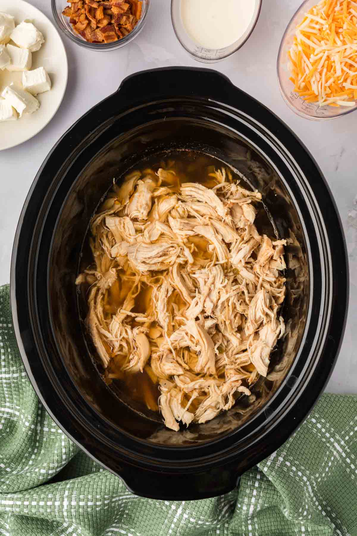 Cooked shredded chicken placed in the slow cooker