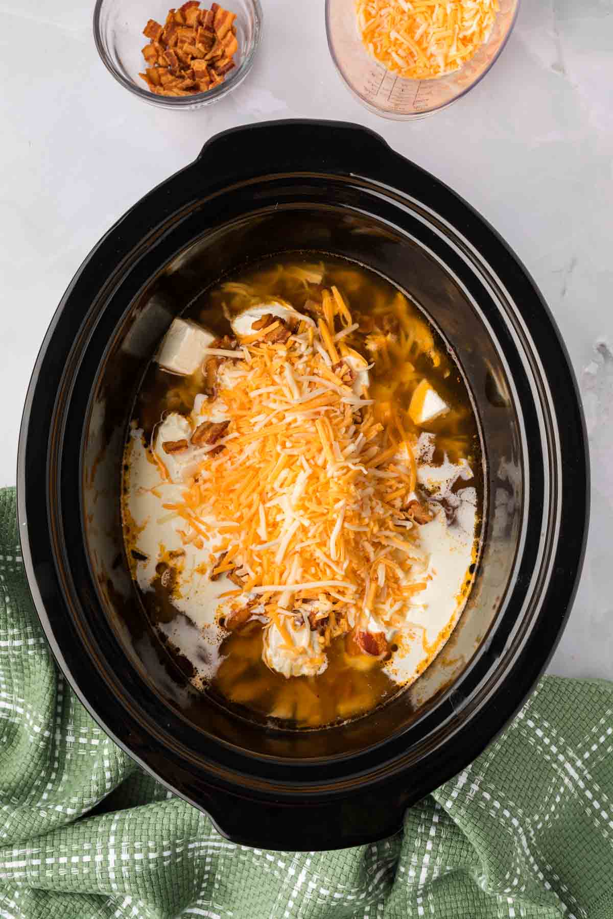 Shredded cheese, cream cheese topped with shredded chicken in the slow cooker