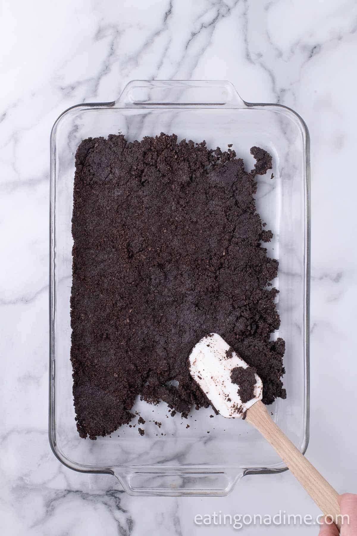 Pressing the Oreo Crust in the baking dish with a spatula