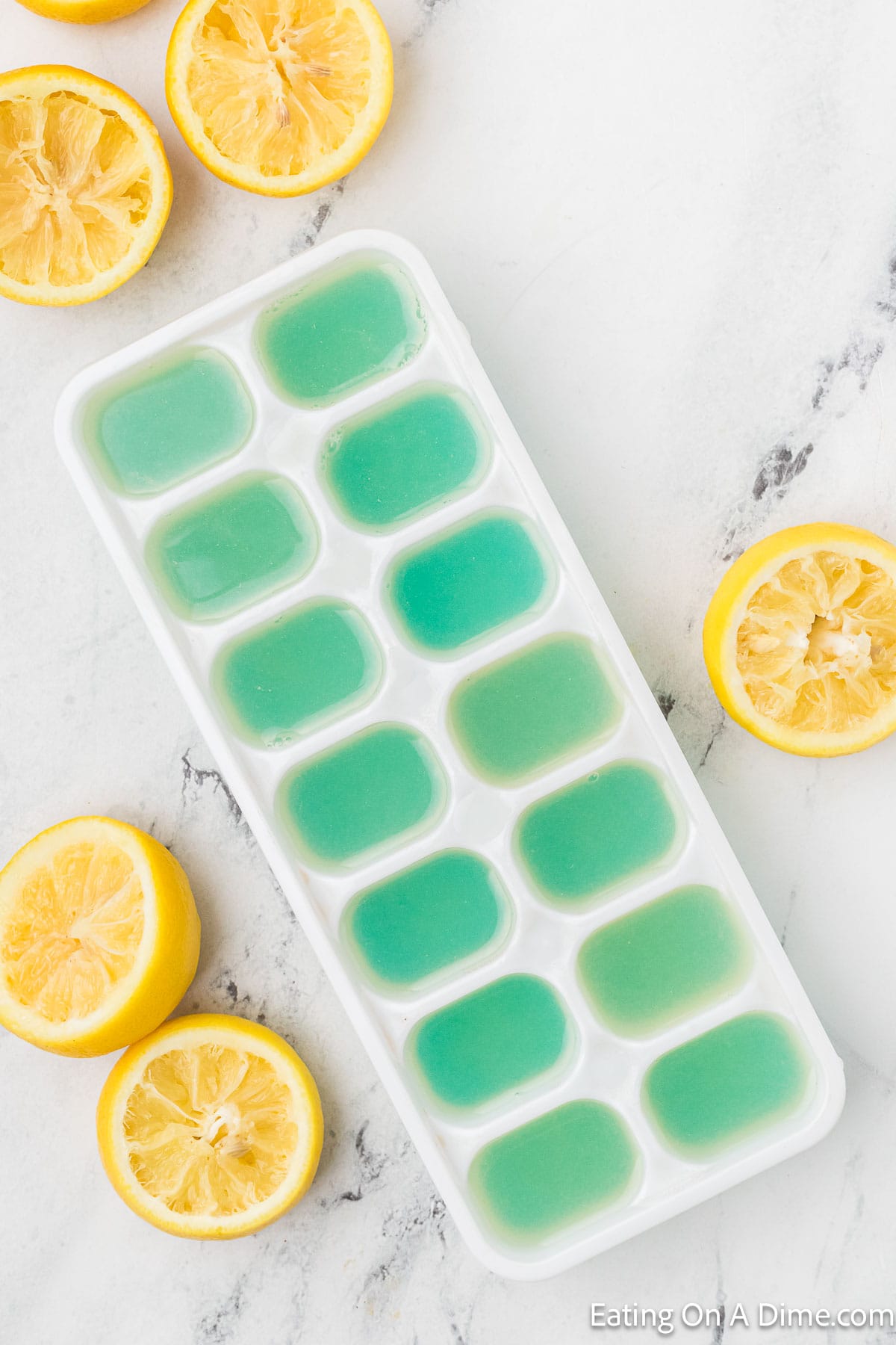Lemon Juice Filled Ice Cube Tray with slice of lemon on the side