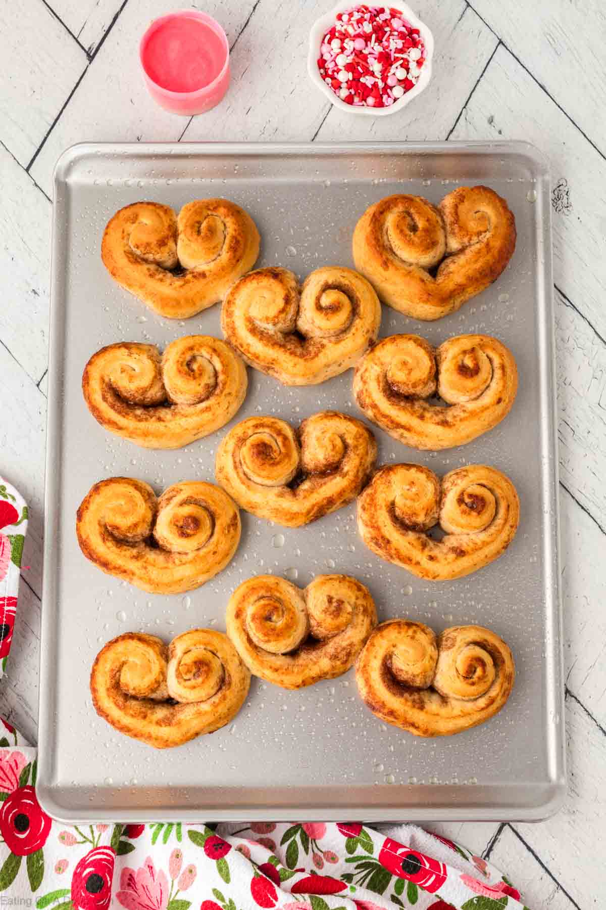 Baked heart shaped cinnamon rolls on a baking sheet