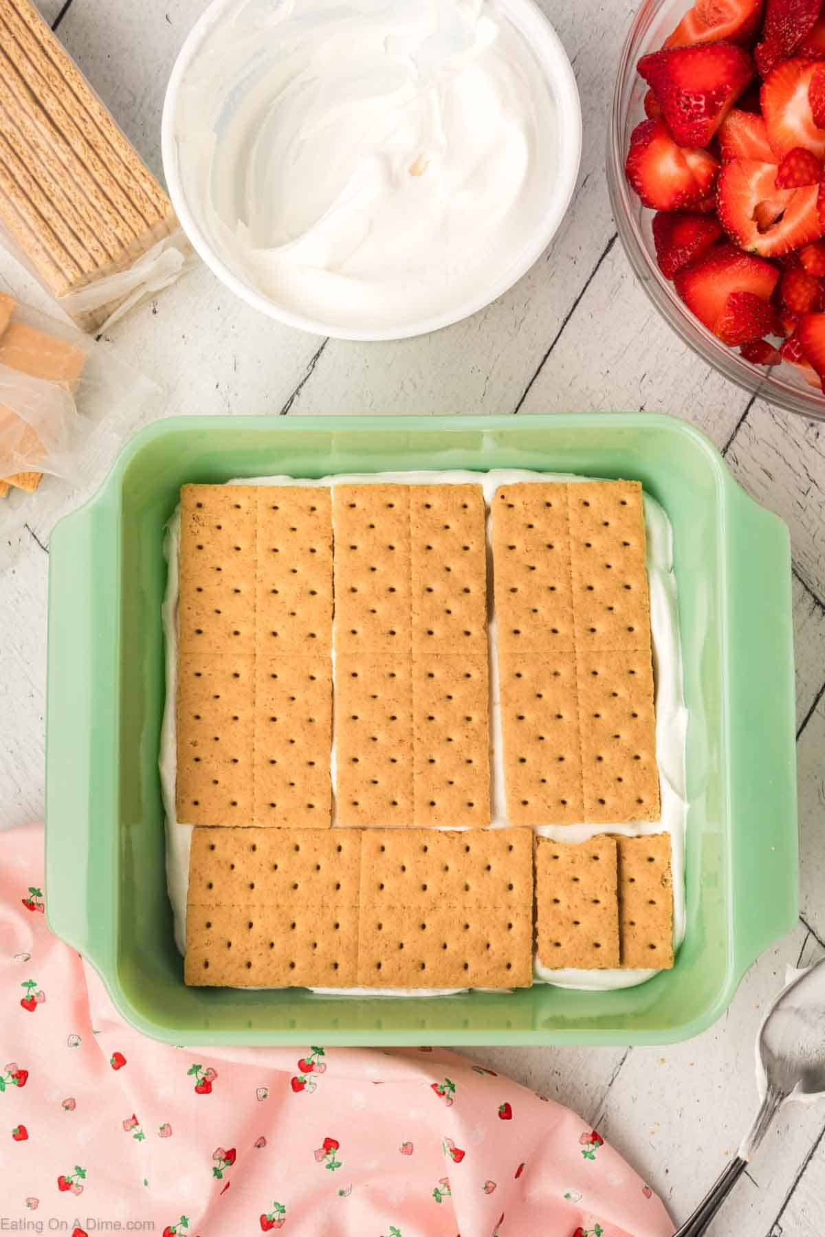 Topping the cool whip with graham crackers in the baking dish