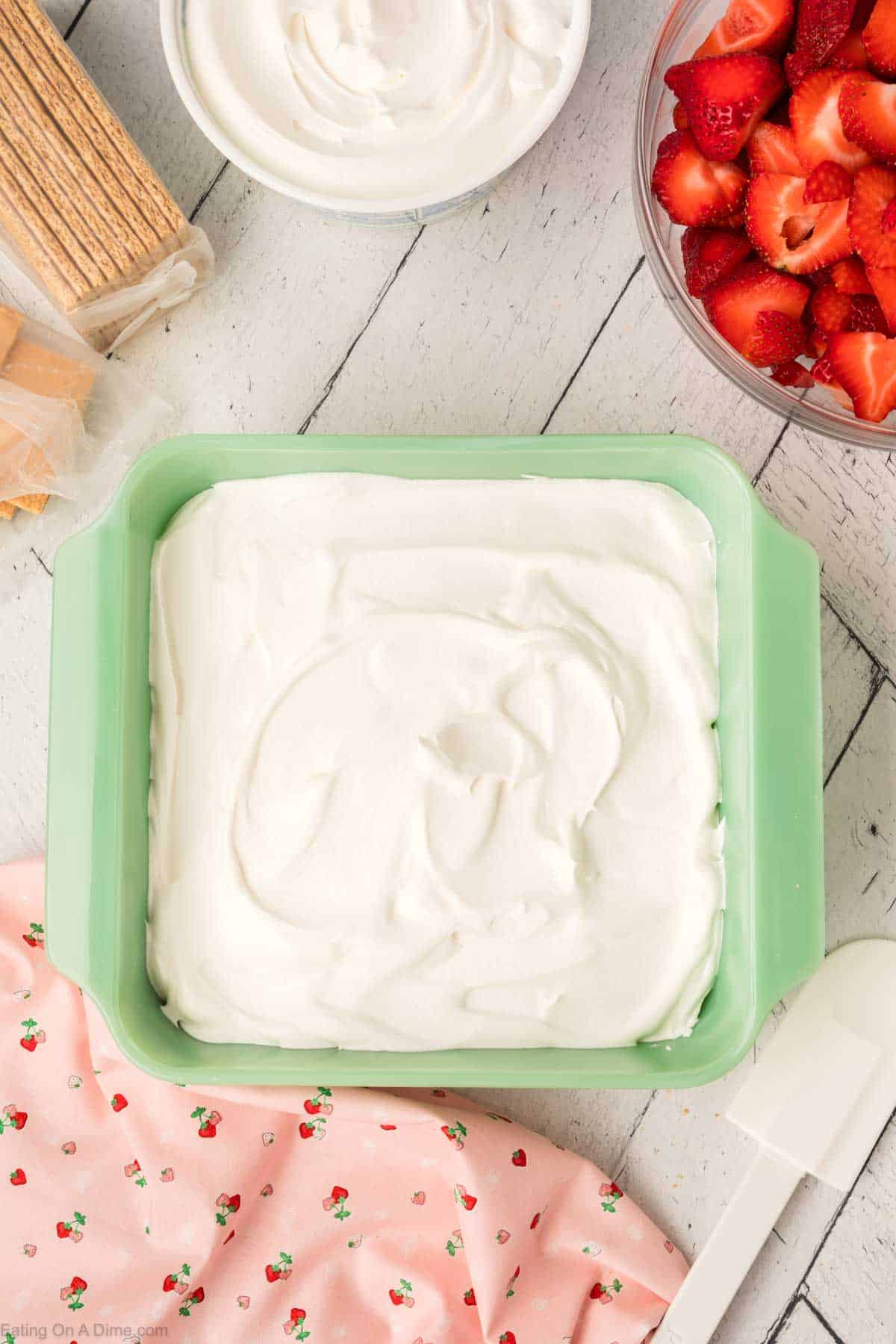 Spreading a layer of cool whip in the baking dish