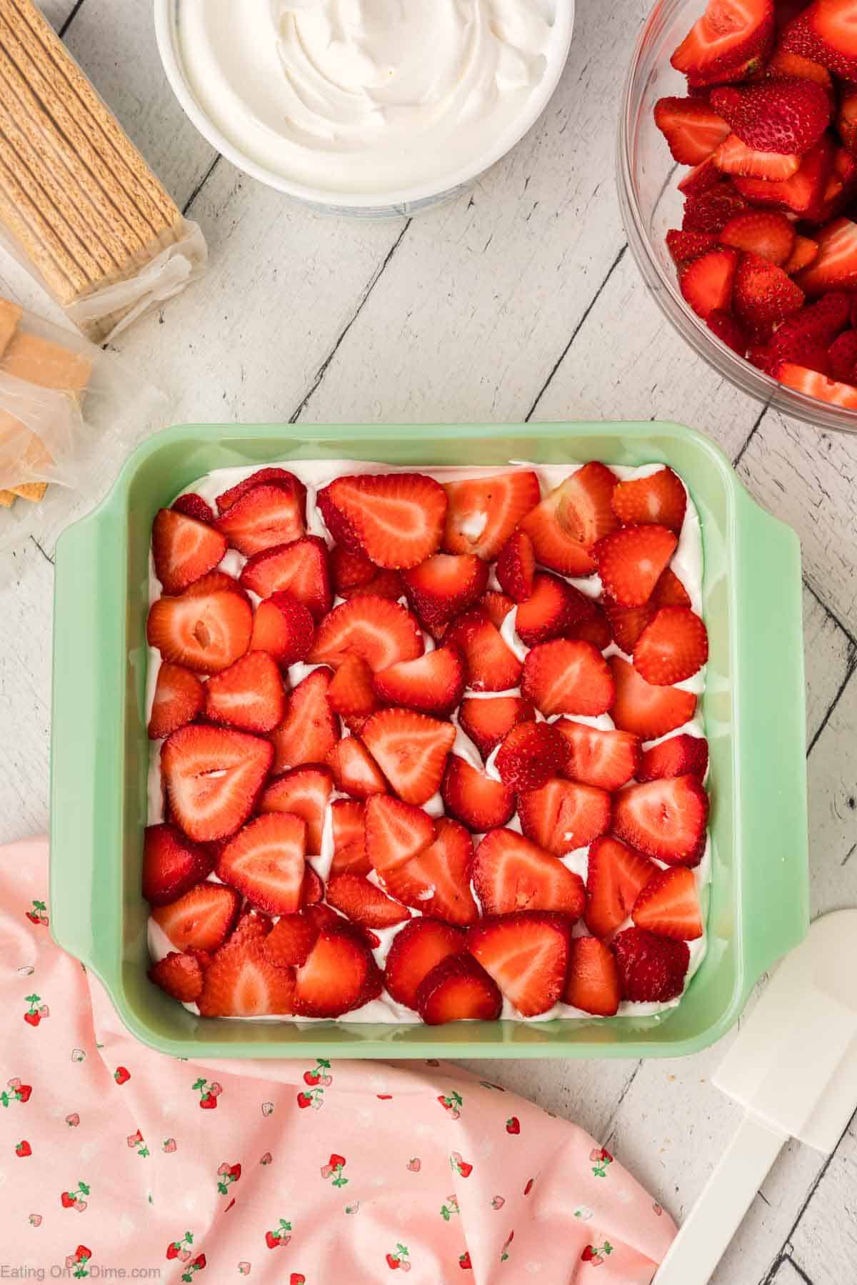 Topping a layer of fresh strawberries in the baking dish