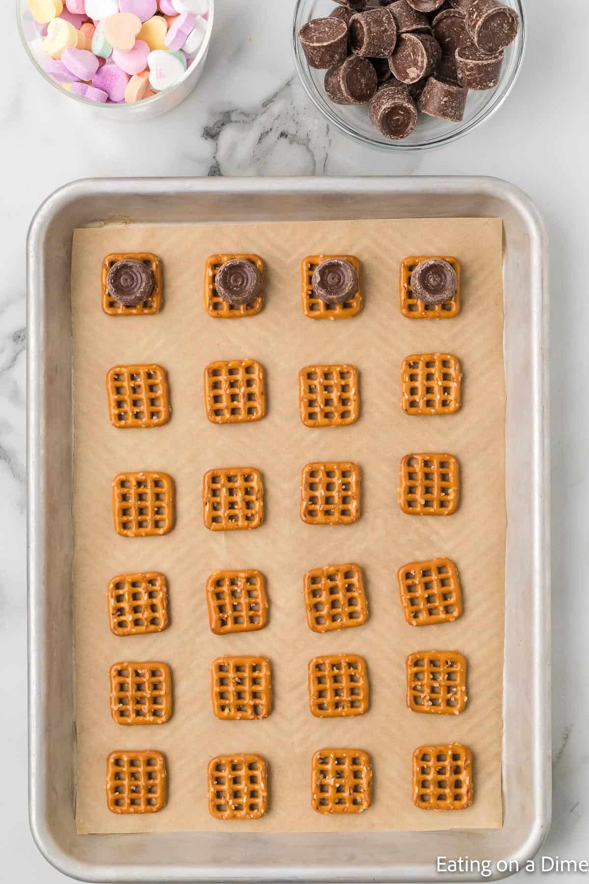 Placing the pretzels on a baking sheet and topping with Rolo Candy