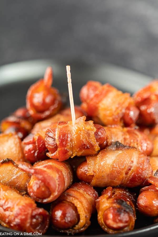 Close up image of bacon wrapped lil smokes on a platter with one that has a toothpick