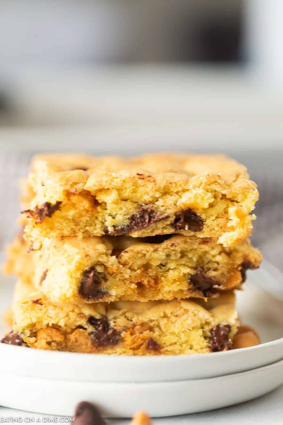 These butterscotch chocolate chip cookie bars are easy to make with only 5 ingredients! These cake mix cookie bars are simple and easy to make in under 30 minutes. You are going to love this easy dessert recipes. #eatingonadime #cakemixcookiebars #cakemixrecipes #easydessertrecipes Butterscotch Chocolate Bars cut into squares stacked