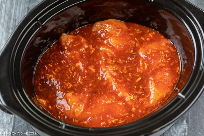 Pouring sauce mixture over the chicken in the slow cooker