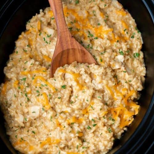 Close up of a wooden spoon scooping out a serving of this chicken and rice from the crock pot.
