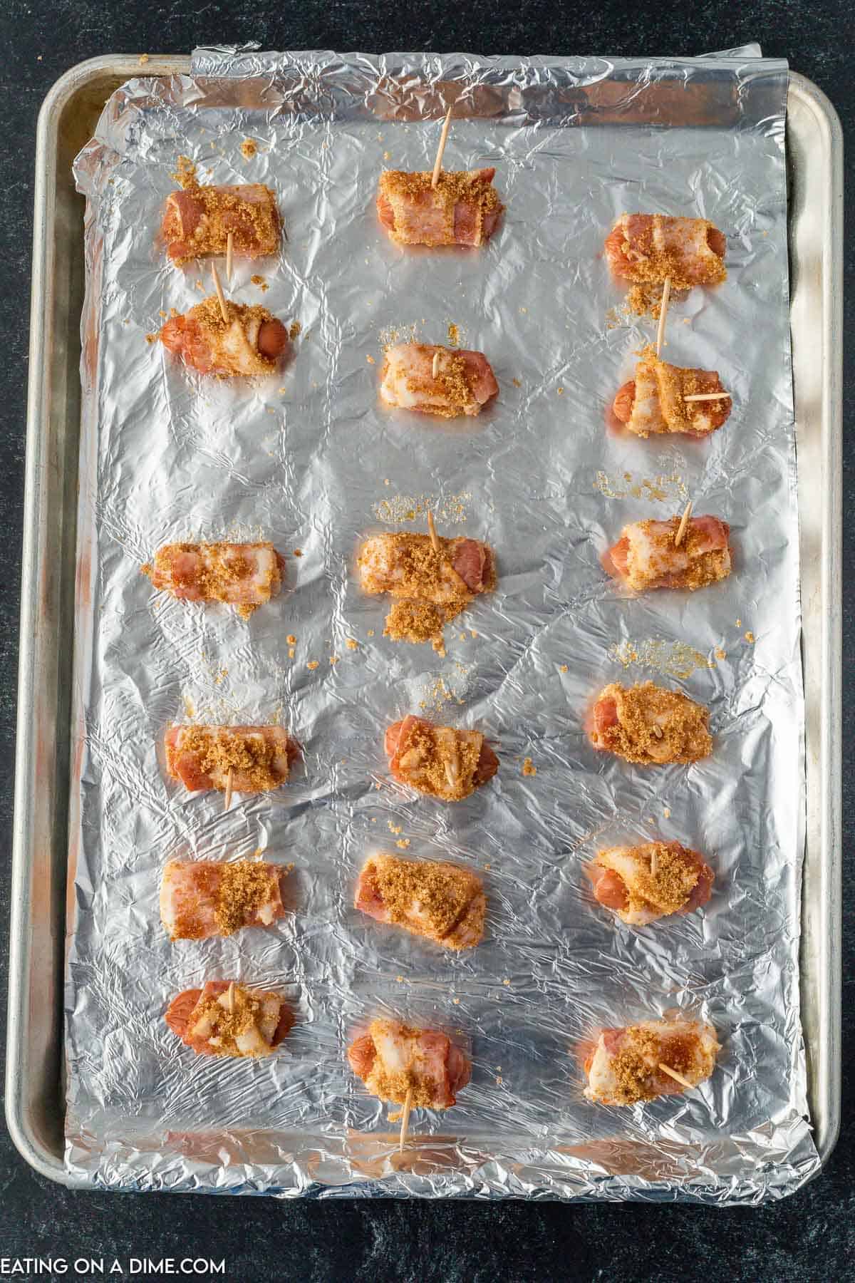 Placing bacon wrapped little smokies on a baking sheet