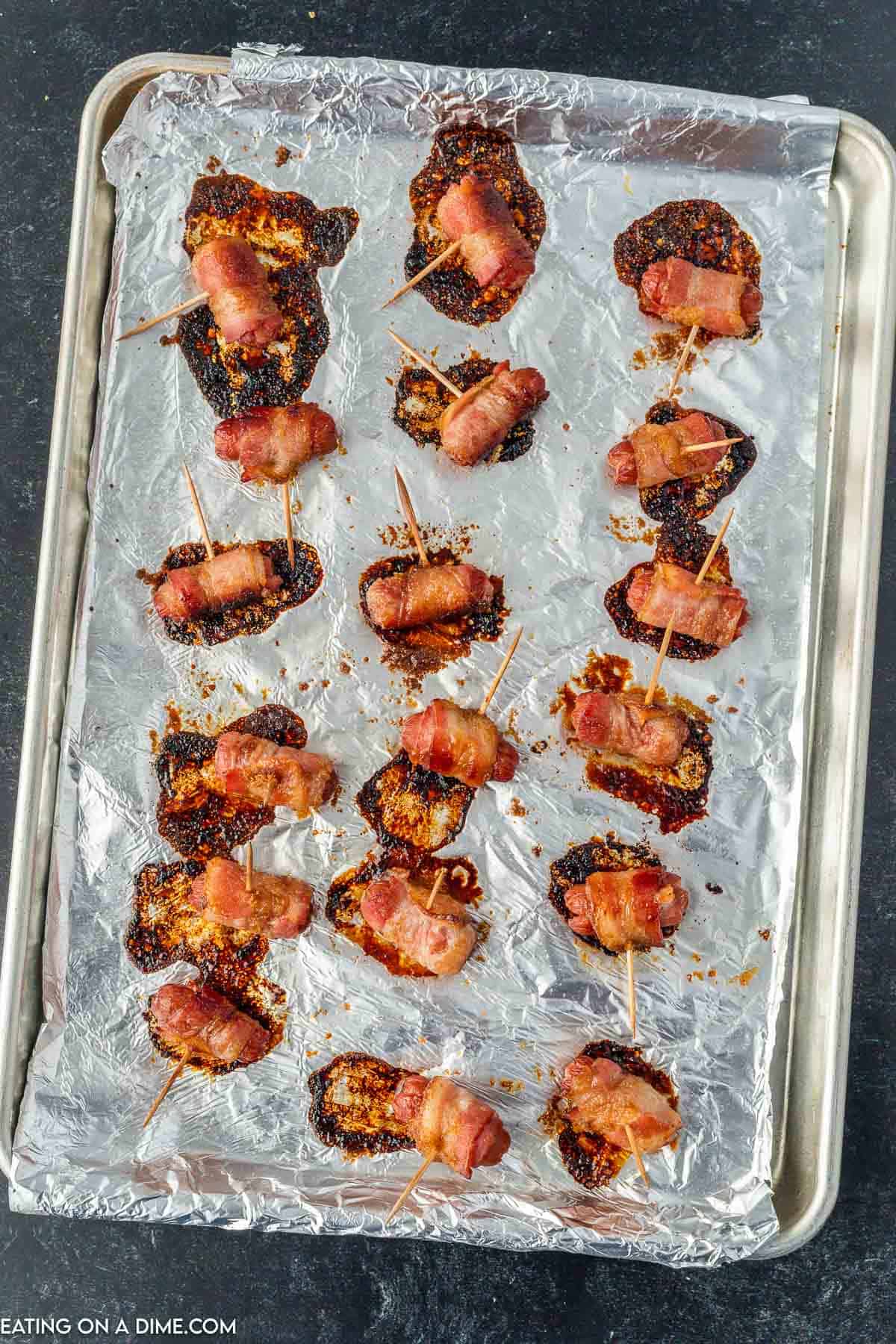 Cooked bacon wrapped little smokies on a baking sheet