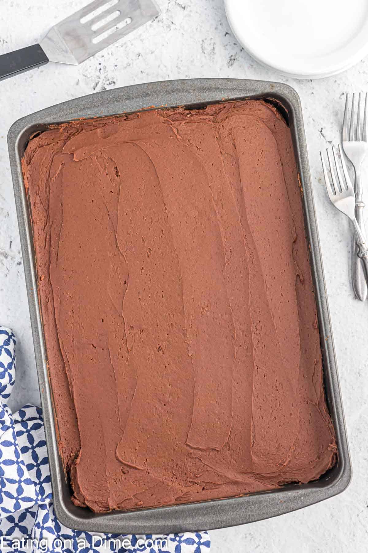 Baked cake topped with chocolate frosting in a baking dish.