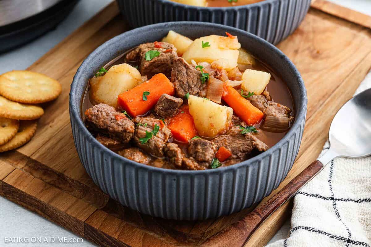 A close-up of a bowl filled with hearty Instant Pot beef stew, featuring chunks of beef, potatoes, and carrots garnished with parsley.
