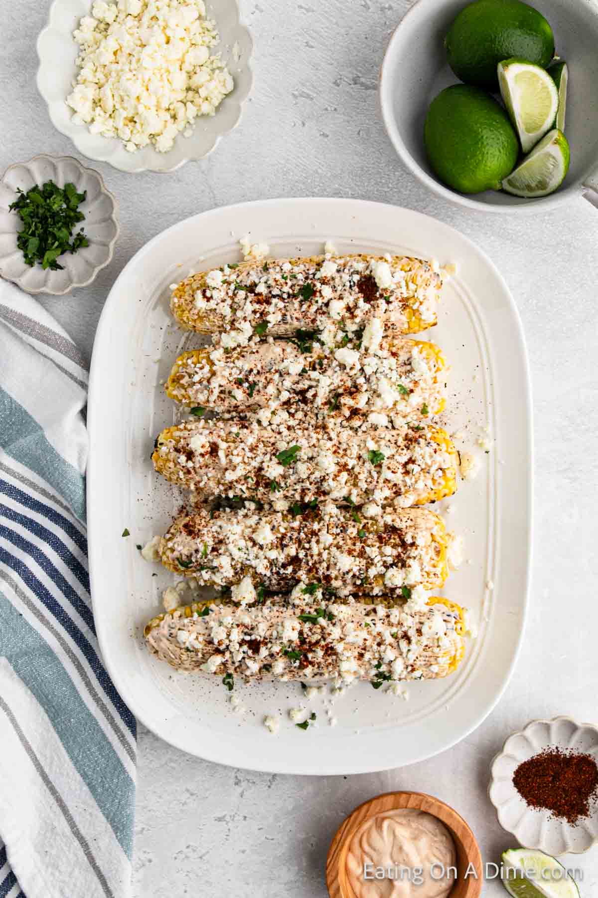 Adding the fresh cilantro and paprika to the top of the Mexican corn on the cob on the platter